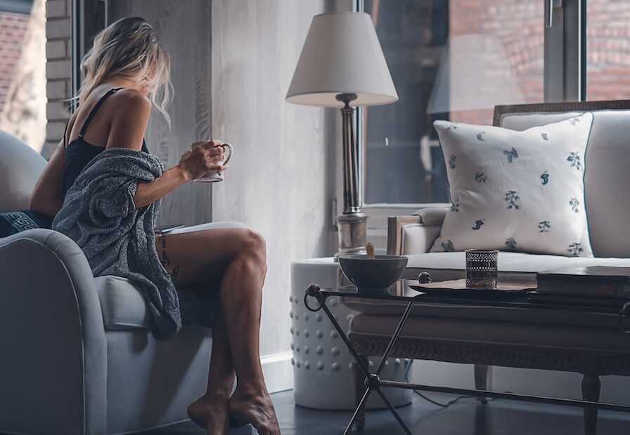 woman sitting on gray sofa chair holding mug